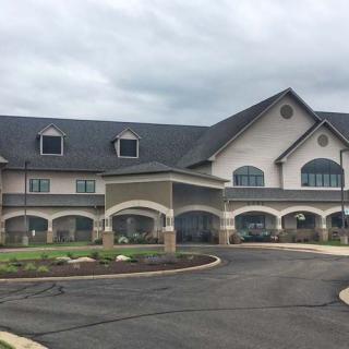 A large building with arched windows and a well-maintained driveway under a cloudy sky.