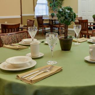 An elegantly set dining table in a restaurant with neatly arranged tableware and a centerpiece plant.