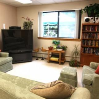 A cozy living room with a television, comfortable seating, and a well-stocked bookshelf.