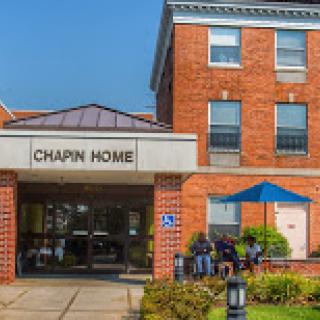 A sunny day at Chapin Home, showcasing its welcoming entrance and outdoor seating area.