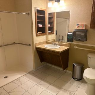 A clean and simple bathroom featuring a shower, toilet, sink, and storage.