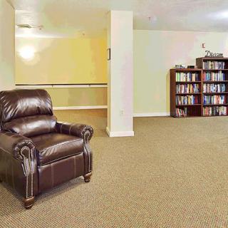 A cozy living room with a leather chair and a fully stocked bookshelf.