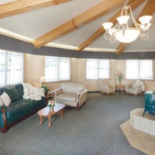 A spacious living room with a circular layout, featuring multiple sofas and chairs, a coffee table, large windows, and a chandelier.