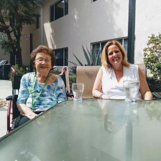 Two women sitting at a table outside, enjoying a sunny day.