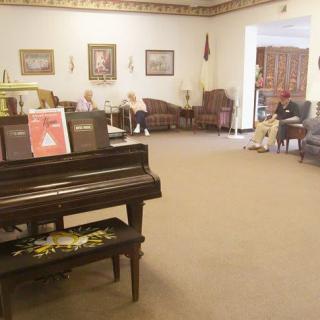 A lobby with a piano, seating area, and people sitting around.