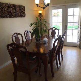 A cozy dining room with a wooden table and elegant chairs, accented by a plant centerpiece and soft lighting.