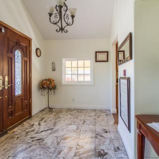 A well-lit foyer with marble flooring, a wooden front door, and elegant decor.
