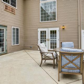 A cozy patio with outdoor seating and a table set against a brick exterior.