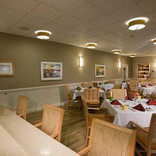 A spacious restaurant dining area with neatly arranged tables and chairs, warm lighting, and tasteful decor.