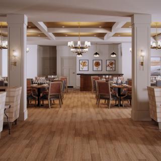 A spacious and elegantly designed restaurant dining area with wooden floors, comfortable seating, and stylish lighting.