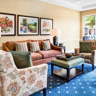 A cozy living room with a sofa, two armchairs, and a coffee table, adorned with decorative artwork on the walls.