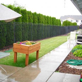 A suburban backyard featuring a raised garden planter and a well-maintained lawn.