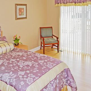 A cozy bedroom featuring a floral bedspread and natural light streaming through the curtains.