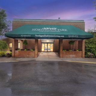 The exterior entrance of a building with a green awning illuminated at night.