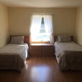 A bedroom with two twin beds and a window letting in natural light.