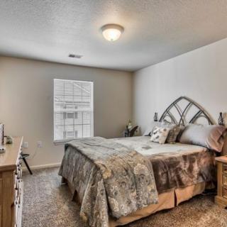 A cozy bedroom with a neatly made bed and natural light coming through the window.