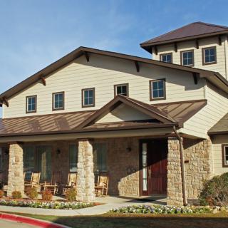 A two-story residential house with a stone exterior and a spacious porch.