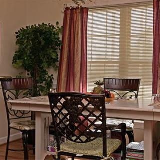 A cozy dining room with a table, chairs, and large windows adorned with curtains.