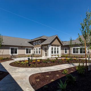 A residential building with a landscaped garden and pathway under a clear blue sky.