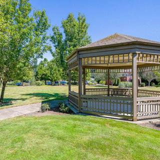 A picturesque gazebo in a lush green park with a clear blue sky.