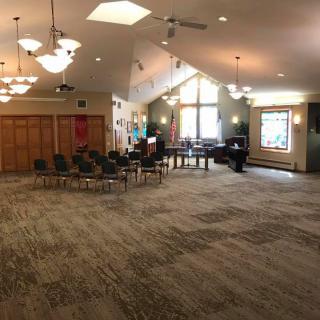 A spacious interior of a community center with chairs arranged in a circle and large windows providing natural light.