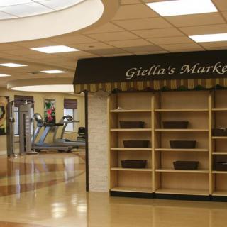An indoor market scene with empty shelves and visible exercise equipment in the background.