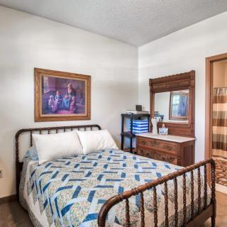 A cozy bedroom with vintage furniture and a colorful quilt on the bed.