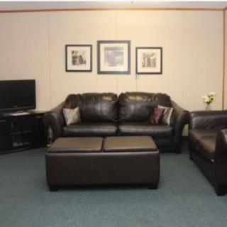 A cozy living room with leather sofas, a coffee table, and a TV.