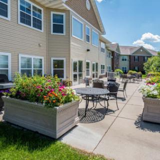 A beautifully landscaped outdoor patio space with tables and flowering plants, perfect for relaxation on a sunny day.