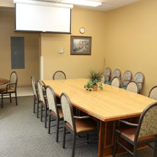 A spacious meeting room equipped with a long table and chairs, ready for discussions or presentations.