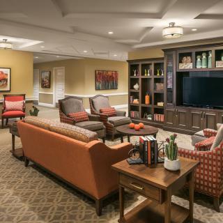 A cozy living room featuring comfortable seating, a large television, and a well-organized bookshelf.