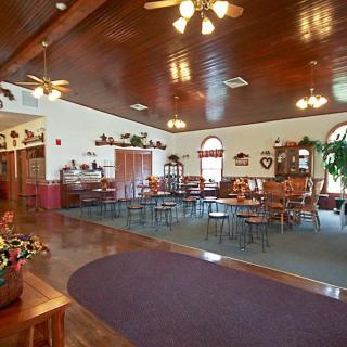 A spacious restaurant interior featuring wooden ceilings, ceiling fans, and neatly arranged tables and chairs.