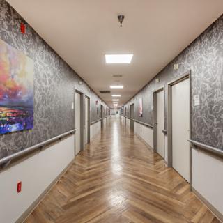 A modern hallway featuring decorative artwork, wooden flooring, and a series of doors.