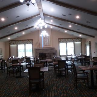 A spacious dining area with tables and chairs, featuring large windows that let in natural light.