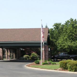 A building entrance with a flagpole and surrounding trees and landscaping.