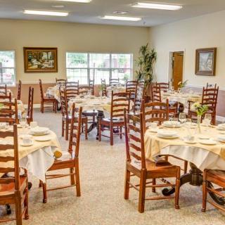 An empty dining room with neatly set tables and wooden chairs.