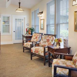 A cozy waiting room with floral-patterned chairs and soft lighting, complemented by a window view and decorative elements.