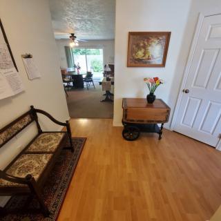 A cozy entrance hallway with a bench, artwork on the wall, and a vase of flowers on a small table.