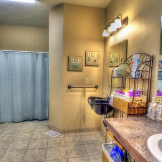 A well-lit bathroom featuring a sink, mirror, and shower curtain with decorative elements.