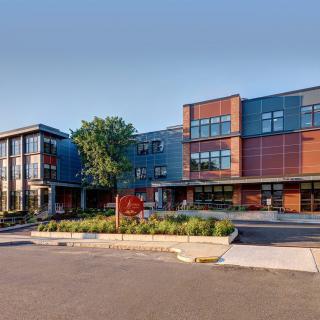 A modern school building with landscaped entrance and a clear blue sky.
