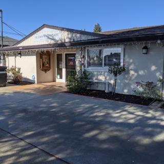 A charming residential house with a well-maintained driveway and front yard, set against a clear blue sky.