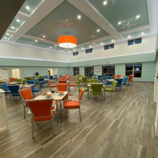 A modern dining area featuring colorful chairs and spacious layout, illuminated by stylish lighting.