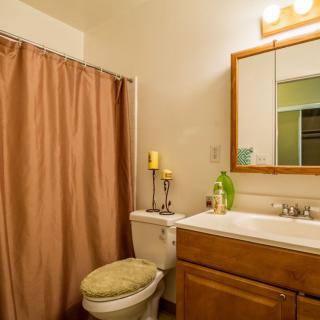 A cozy bathroom with a shower curtain, sink, mirror, and decorative candles.