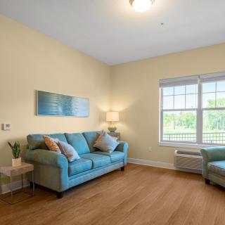 A cozy living room with a blue sofa, matching armchair, and wooden flooring.