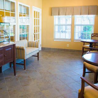 A cozy waiting room with chairs, tables, and large windows.