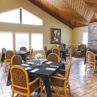 A cozy restaurant dining area with wooden ceilings and neatly arranged tables.