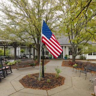 A serene courtyard with an American flag surrounded by trees and outdoor seating.