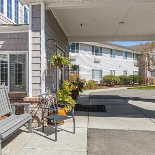 A welcoming entrance to a residential building with benches and plants.