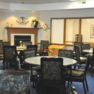 A cozy dining room with round tables and a fireplace.