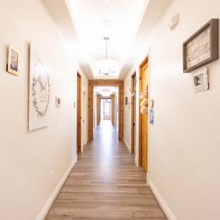 A brightly lit hallway with wooden doors and decorative wall hangings.